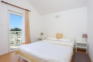 Dormitorio blanco con cama y ventana grande en Apartments by the sea Rogoznica - 4162, en Rogoznica