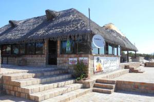 Casa Coco Palmeira في إنهامبان: مبنى مع سقف من القش مع سلالم في الأمام
