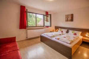 ein Schlafzimmer mit einem Bett und einem roten Sofa in der Unterkunft Haus Niedermättle in Oppenau