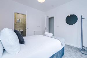 a white bedroom with a bed and a bathroom at Cosy 3 bed 3 bath house - Central Liverpool -Self Check-In & Free Parking! in Liverpool