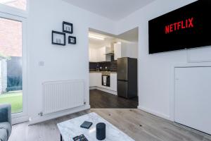 a living room with a tv on a wall at Cosy 3 bed 3 bath house - Central Liverpool -Self Check-In & Free Parking! in Liverpool