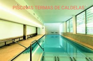 a swimming pool in a building with the words piscina termas de cal at Pensão Continental Machado in Caldelas