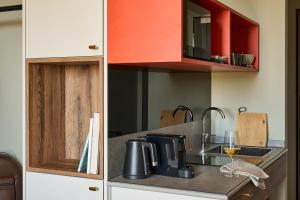 a kitchen with red cabinets and a sink with a wine glass at FREIgeist Homes - Serviced Apartments in Göttingen