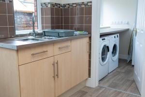 a kitchen with a sink and a washing machine at Russell House, Large townhouse spacious and modern with ground floor bedroom and shower room and free parking in Harraby