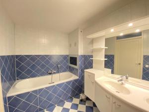 een blauw betegelde badkamer met een bad en een wastafel bij Callantsoger Staete A304 in Callantsoog