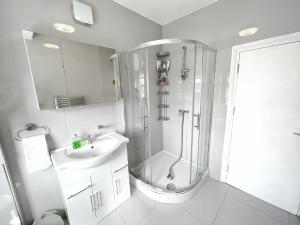 een witte badkamer met een douche en een wastafel bij Luxurious House near Excel- Air Conditioning, 9 Beds, 2 Baths, Garden, fast WiFi in Londen