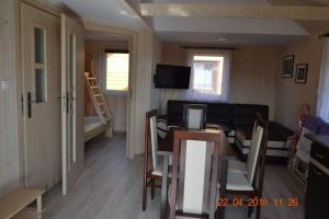 een woonkamer met een tafel en stoelen en een televisie bij Laguna in Rusinowo