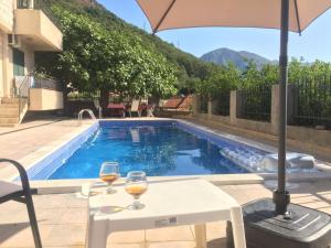 two glasses of wine on a table next to a swimming pool at Kamenari new summer holiday in Kamenari