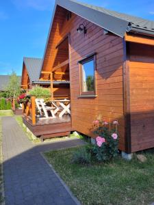 een houten huis met een terras en een raam bij Laguna in Rusinowo