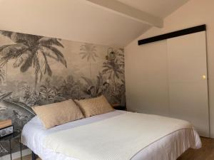 a bedroom with a bed with a tropical wallpaper at Cap Ferret - Villa Sérénité - piscine, proche Océan et Bassin, classée 4 étoiles Meublé de tourisme in Lège-Cap-Ferret +27 photos
