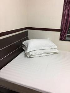 una cama con una almohada blanca encima en Hang Ho Hostel, en Hong Kong