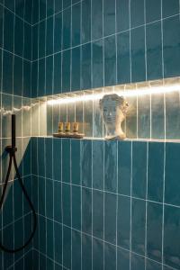 a blue tiled bathroom with a statue of a head on a shelf at Vossia Luxury Rooms & Sicilian Living in Palermo