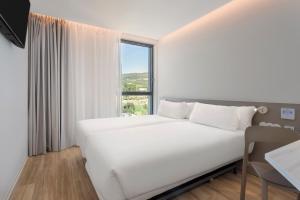 B&B HOTEL Santo Tirso في سانتو تيرسو: سرير أبيض في غرفة بها نافذة