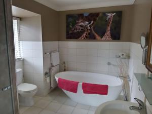 a bathroom with a bath tub and a giraffe picture on the wall at Beautiful Dutch Barn style country house in Merrijig (base of Mt Buller). in Merrijig