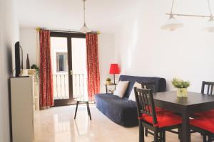 ein Wohnzimmer mit einem Tisch und einem blauen Sofa in der Unterkunft Céntrico Apartamento en Calle Carreteria - Malaga in Málaga