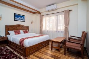 a bedroom with a bed and a desk and a chair at Madhuban Hotel in Kathmandu