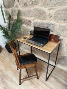 un ordinateur portable assis sur un bureau avec une chaise dans l'établissement Casa Anduriña, à Ourense