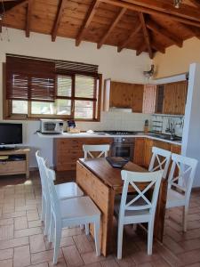 eine Küche mit einem Holztisch und weißen Stühlen in der Unterkunft Paxos villas in Gaios