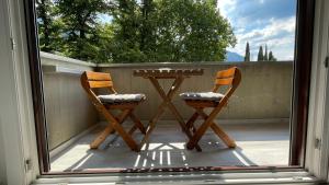 2 sillas y una mesa en un balcón con ventana en La casa sul lago, en Maroggia