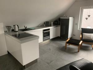 a white kitchen with a counter and a chair at Apartment in toller Lage am Rande des Ruhrgebietes in Bottrop