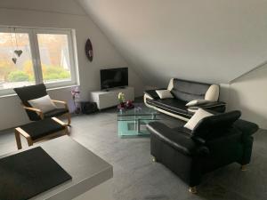 ein Wohnzimmer mit einem Sofa, Stühlen und einem TV in der Unterkunft Apartment in toller Lage am Rande des Ruhrgebietes in Bottrop