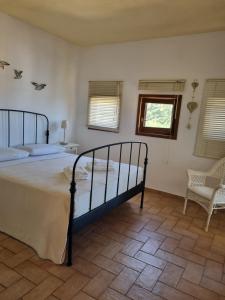 a bedroom with a bed and a chair and a window at Paxos villas in Gaios