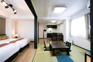 a bedroom with a bed and a table and a kitchen at Minn Machiya in Tokyo