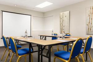 una sala de conferencias con mesas largas y sillas azules en Ramada by Wyndham Madrid Tres Cantos en Tres Cantos