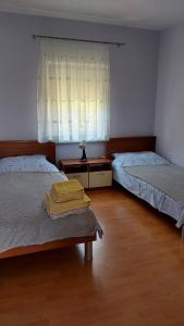a bedroom with two beds and a table and a window at Apartments Bolont in Pag