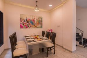 a dining room with a table with chairs and a painting at SaffronStays Aster, plunge pool villa with garden, Lonavala in Lonavala