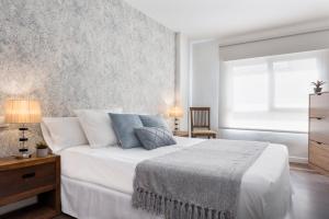 a bedroom with a bed with white sheets and blue pillows at Viviendas con Fines Turísticos "Quivir Pidal" in Andújar