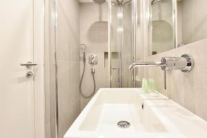 La salle de bains blanche est pourvue d'un lavabo et d'une douche. dans l'établissement Earls Court East Serviced Apartments by StayPrime, à Londres