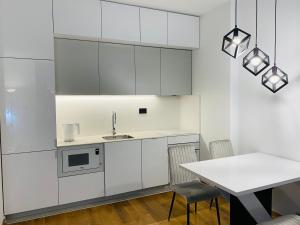 a kitchen with white cabinets and a table with chairs at Oasis in Jajinci +4 photos