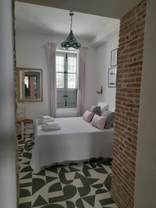 a bedroom with a bed and a brick wall at La AMARA Farah - en el casco antiguo de Frigiliana in Frigiliana