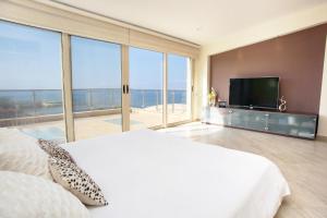 a bedroom with a large white bed and a flat screen tv at Seafront 5 Bedroom Villa Paradise in Sea Caves in Peyia