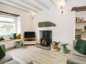 a living room with a fireplace and a tv at Turn Cottage in Ulverston