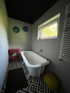 baño con bañera blanca y ventana en Hangvilla vendégház, en Miskolc
