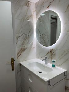 Un baño blanco con lavabo y espejo. en Apartamento LA GRACIA, en Roquetas de Mar
