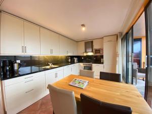 a kitchen with a wooden table and white cabinets at Callantsoger Staete A305 in Callantsoog +4 photos