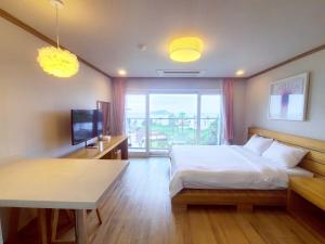 a bedroom with a bed and a table and a window at Dombe Resort in Seogwipo