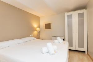 um quarto com uma grande cama branca e 2 toalhas brancas em Lodging Apartments Sagrada Familia em Barcelona