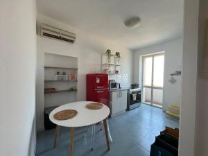 a kitchen with a white table and a red refrigerator at You and Me Cagliari in Cagliari
