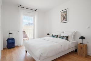 a white bedroom with a large white bed and a window at Edgar Suites - Meudon-la-Forêt in Meudon
