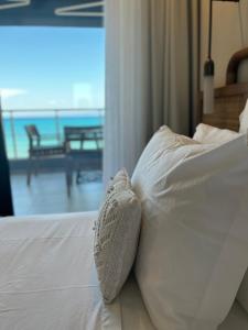 a white pillow on a bed with a view of the ocean at Adriana beach in Pefkochori