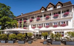 a hotel with tables and umbrellas in front of it at Hotel & Restaurant Sonne in Kirchzarten