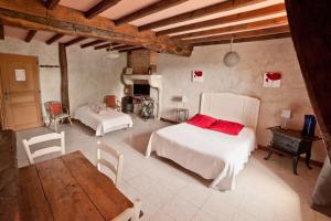 1 dormitorio con 2 camas, mesa y chimenea en Ferme de Malo, en Étrigny