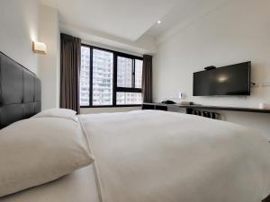 a white bedroom with a large bed and a flat screen tv at CHECK inn Express Taichung Fuxing in Taichung