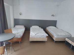 two beds in a room with a table and a table at WOSiR Drzonków in Zielona Góra