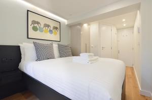 a bedroom with a bed with white sheets and pillows at Earls Court East Serviced Apartments by StayPrime in London