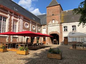 a large brick building with red umbrellas in a courtyard at le chateau de PENIN in Penin